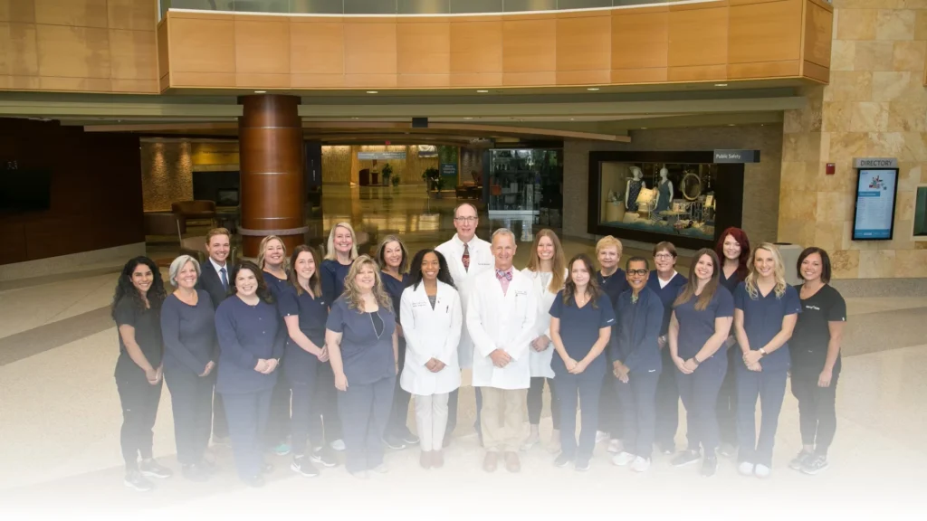 Dr. Waite and Associates dental team posing together in modern office lobby.